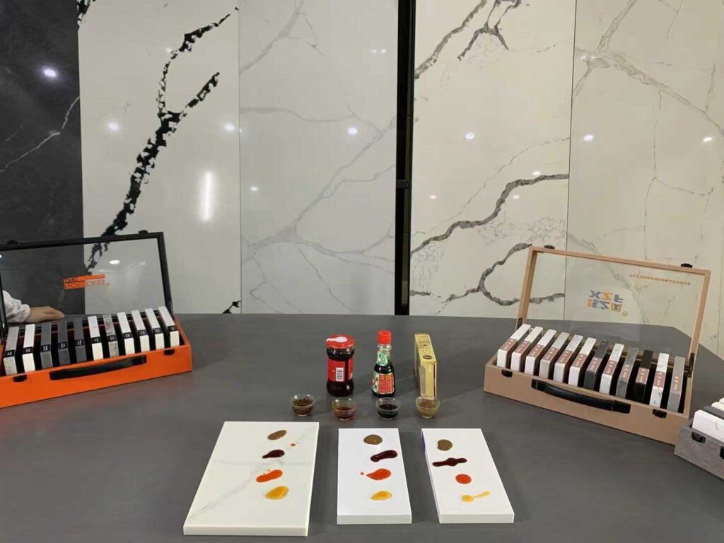 Warner Quartz stone samples undergoing stain resistance test with soy sauce, tea, vinegar, and chili sauce in a laboratory setting.