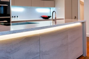 A contemporary kitchen with a large white quartz island worktop and dark blue cabinetry, showcasing 2025 design trends.